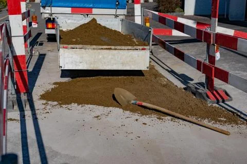 Trailer on construction site with open tailgate and sand on the street. Stock Photos