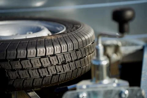 Trailer spare wheel mounted on frame near coupling handle Stock Photos