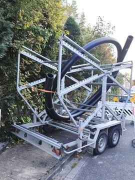 A trailer with a spool of large diameter black plastic pipes for laying 스톡 사진