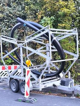A trailer with a spool of large diameter black plastic pipes for laying Stock Photos