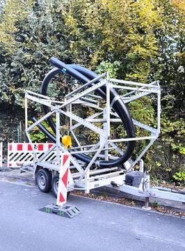 A trailer with a spool of large diameter black plastic pipes for laying 스톡 사진