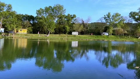Trailers of mobile vacation homes shore camping pond in the morning sunlight Stock Footage 197571704