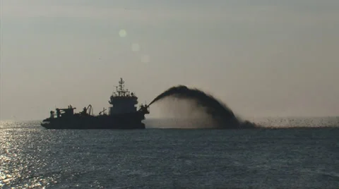 Trailing suction hopper dredges rainbowing near seawall + zoom out Stock Footage 36868565