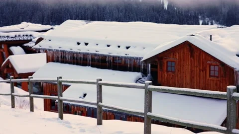 Trails in the snow leading toward small village on a cold winter evening 動画素材 145333002
