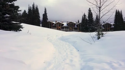 Trails in the snow leading toward small village on a cold winter evening Vídeo Stock 145333399