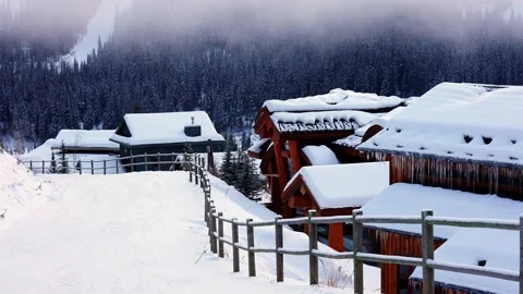 Trails in the snow leading toward small village on a cold winter evening 動画素材 145333427