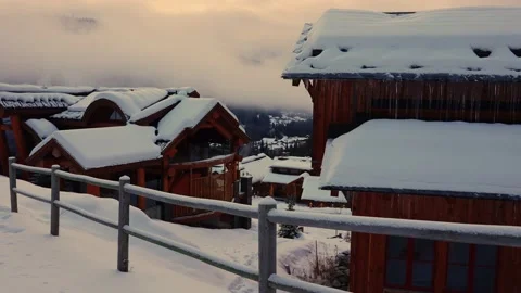 Trails in the snow leading toward small village on a cold winter evening Vídeo Stock 145333467