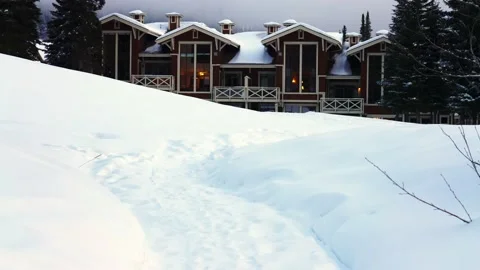 Trails in the snow leading toward small village on a cold winter evening Vidéo 145333479