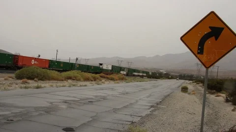 Train and Car Pass Bullet-Hole Sign in Palm Desert Stock Footage 82447293