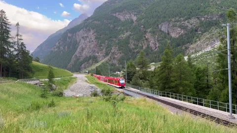 Train and Jungfrau mountains in background, Red modern passenger train is moving Stock Footage 314582519
