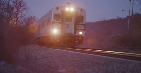 Train approach from around corner at dusk with lens flare dutch angle Video stock 249253699