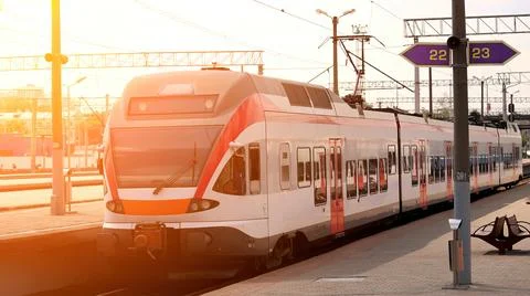 Train arriving at the platform as the sun sets in a peaceful suburban railw.. Stock Photos