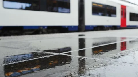 Train arriving in station seen in reflection on platform floor after rain Видео 219775067