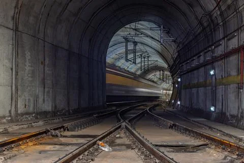 A train blurs through the dark, arched tunnel of Rossio Train Station, creati Stock Photos