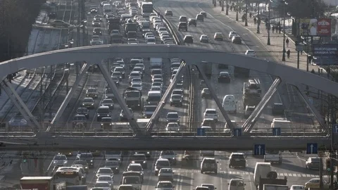 Train on the bridge above a highway in the city, slow motion Stock Footage