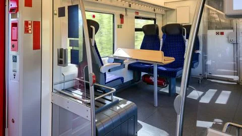  Train carriage interior featuring blue checkered seats and wooden tables. Stock Photos