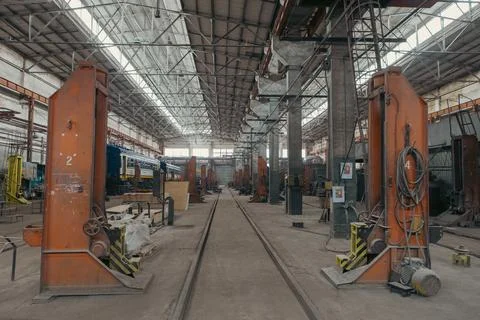 Train carriages stand in a workshop at a train construction and repair plant. Stock Photos
