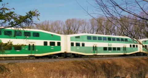 Train carries passengers past spring trees. Close-up of train going on rails at Stock Footage 249663519