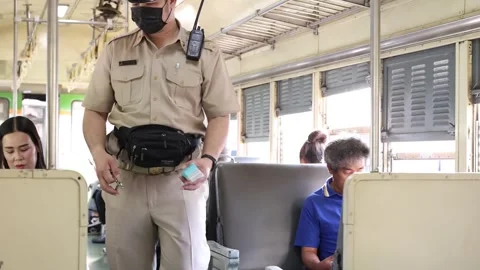 Train conductor checking passenger tickets inside Bangkok commuter carriage Stock Footage 323683166