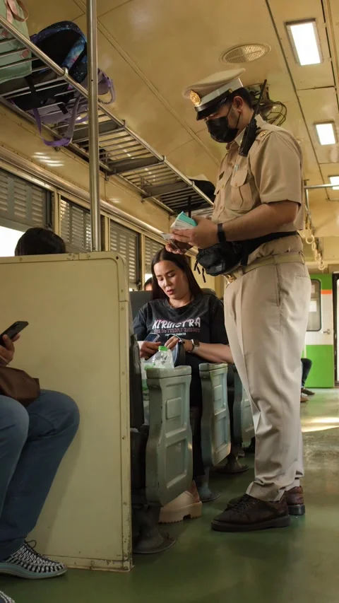 Train Conductor Checking Tickets of Passengers on a Commuter Train in Bangkok Stock Footage 328131895