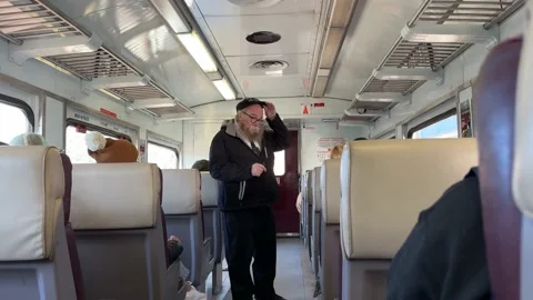 Train conductor or guard walks through carriage checking tickets Stock Footage 226128847