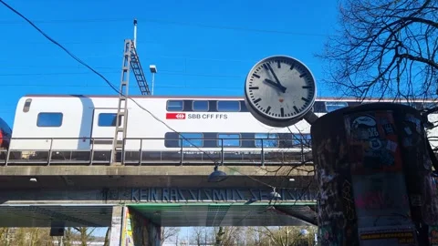 Train crosses a bridge behind a large clock, its hands spinning erratically in Stock Footage 305230831