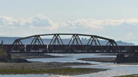 Train Crosses Bridge Over River Near Waterfront Stock Footage 22666499