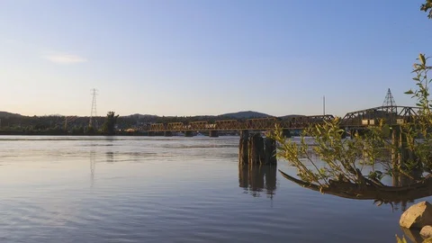 Train crossing bridge over river at sunset Stock Footage 112364818