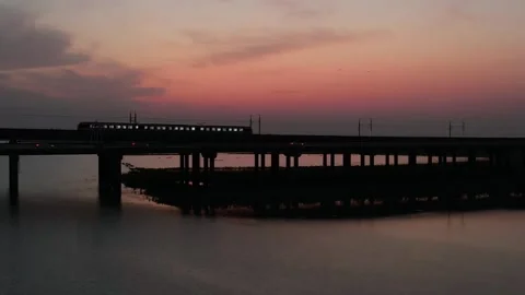 Train Crossing Long Bridge At Red Sunset in Shijiu Lake, China Stock Footage 344039794