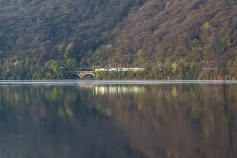 Train crossing old bridge over calm lake water Stock Photos
