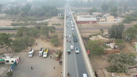 Train Crossing Under a City Bridge in Sahiwal, December 29, 2024 - Drone Aer Stock Footage 309201939