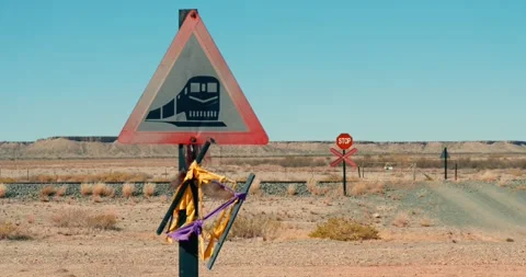 Train Crossing Warning Sign on Desert Road with Tracks in Background Stock Footage 321771583