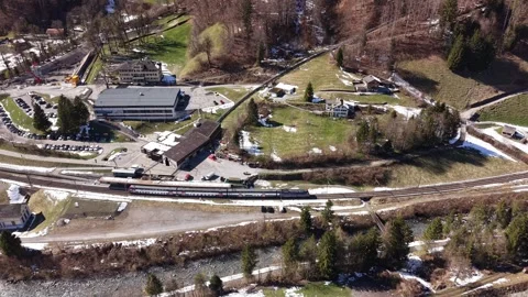 Train departing small alpine station Видео 332134474