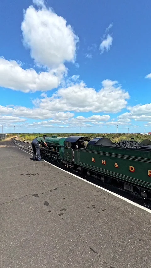 Train driver inspecting the engine of a steam train at the railway station Stock Footage 281102275