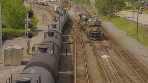 A train engine pulls up alongside a long string of oil tankers on the Stock Footage 247241830