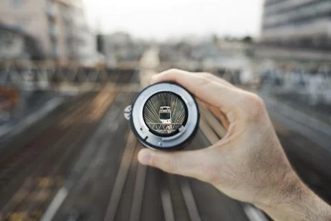 Train entering frame through handheld lens on railway bridge Stock Photos