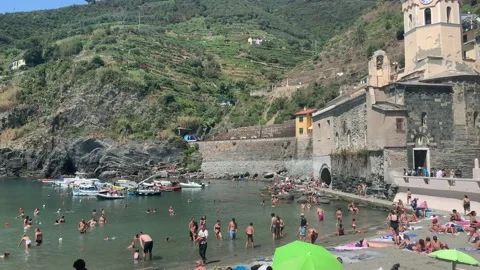 Train is entering a mountain tunnel at Cinque Terre. Crowded beach Stock Footage 159368936