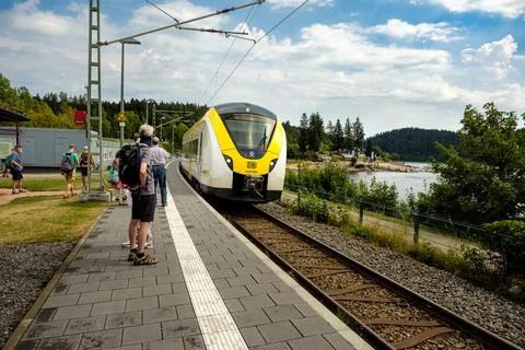 Train enters railway station while passengers waiting on the platform, Schluc Stock Photos