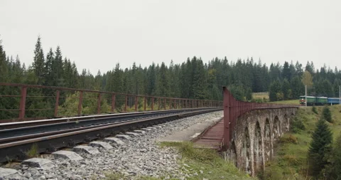 Train goes over the bridge with an old stone viaduct. Train crossing a beautiful Stock Footage 186553827