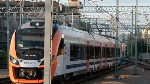 The train goes to the station along the train tracks next to a tall building Video stock 245098193