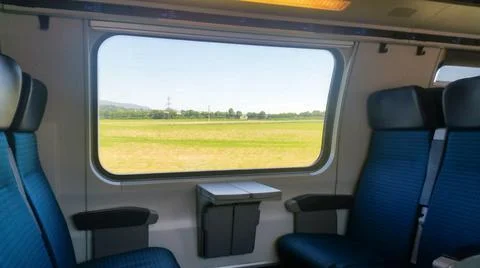 Train is going with empty seats and landscape can be seen on window Stock Photos