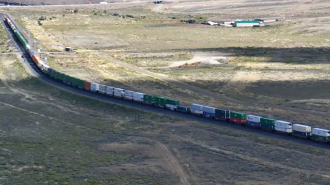 Train hauling wagons through the desert steppe under a brilliant blue sky. Vídeo Stock 252040562