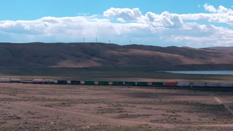 Train hauling wagons through the desert steppe under a brilliant blue sky. Stock-Footage 252044948