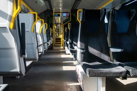 Train interior shows empty seats and yellow handrails during a journey in day Stock Photos