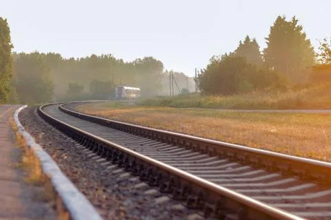 Train leaving on railroad on a beautiful foggy morning  with trees Stock Photos