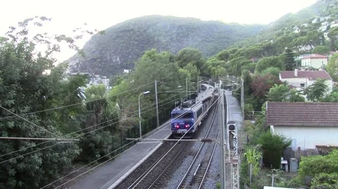 Train leaving a station surrounded by hills Stock Footage 68355767