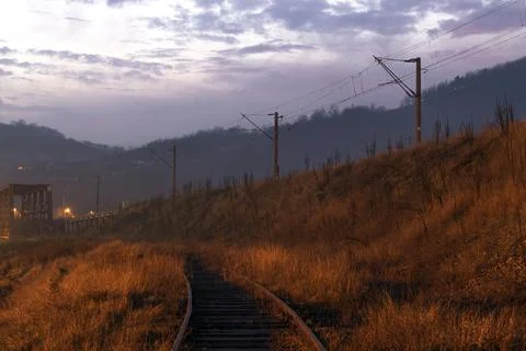 Train line approaching a bridge at sunset Stock Photos