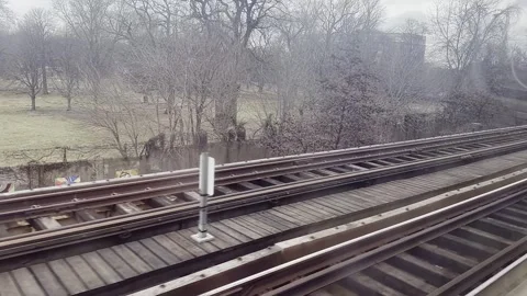 A train moves along the tracks, passing by a serene park with bare trees an.. Stock Footage 301359651