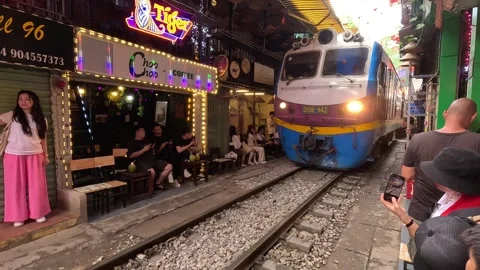 Train moves through narrow Hanoi Train Street, tourists capture the moment. Stock-Footage 317752543