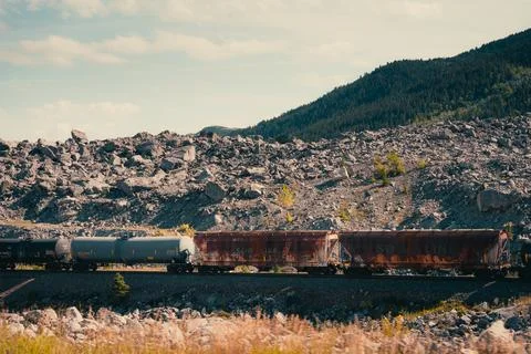 A train moves through a rocky landscape, a blend of nature and industry. Stock Photos